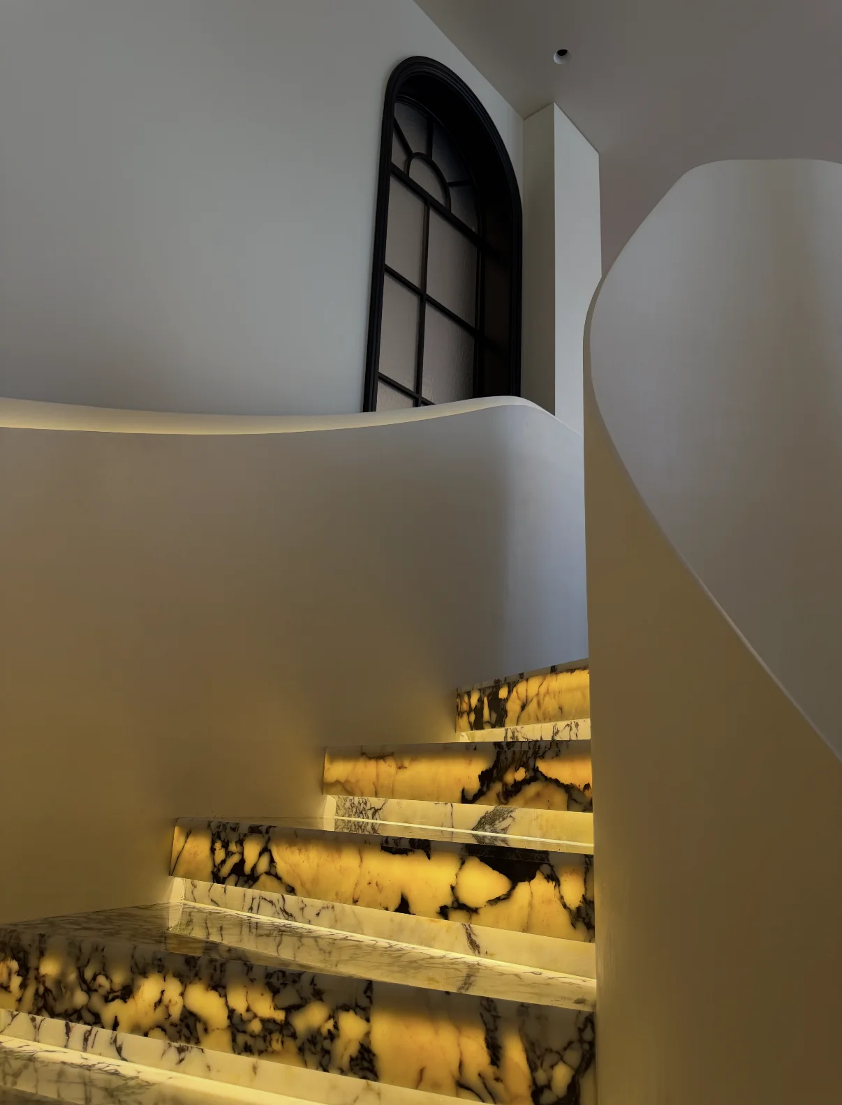 Backlit stone curved staircase in a luxury interior