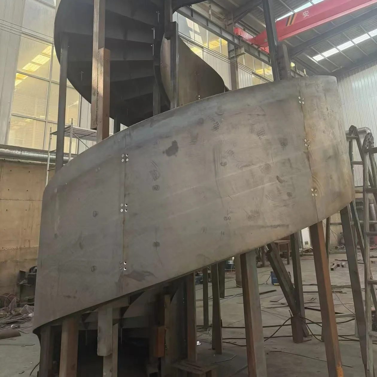 Curved steel plate components being formed and assembled for a custom staircase