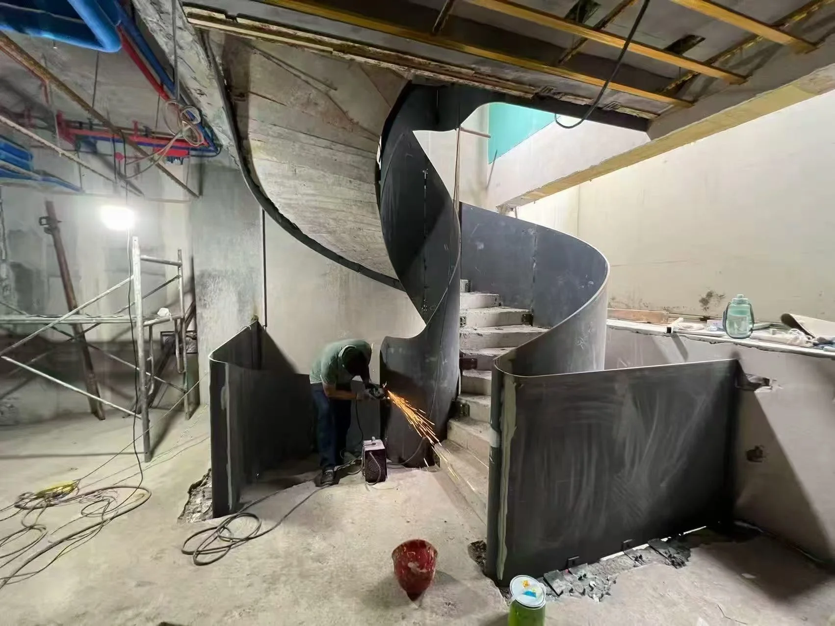 Custom curved steel staircase under on-site installation with steel plate welding and structural assembly