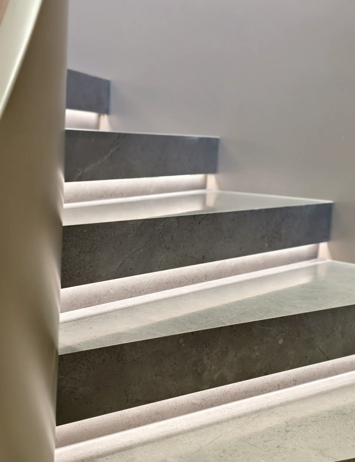 Illuminated curved staircase with stone treads and warm integrated lighting