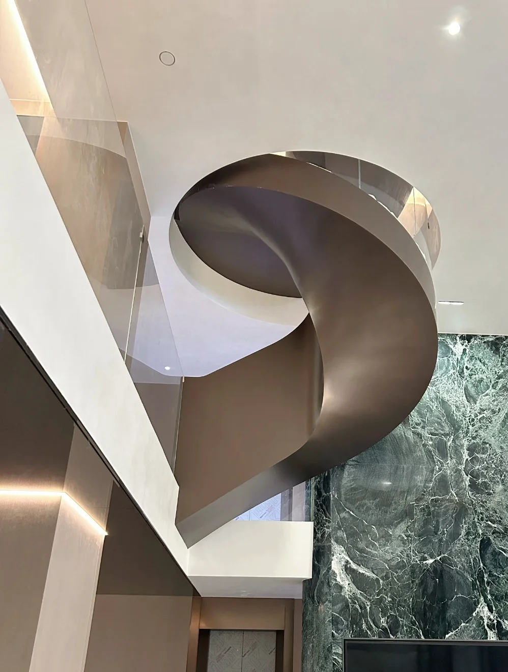 Sculptural curved steel plate detail on a custom helical staircase